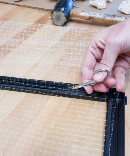 excess mesh grid being trimmed from an Innovative Marine SafeScreen DIY Top